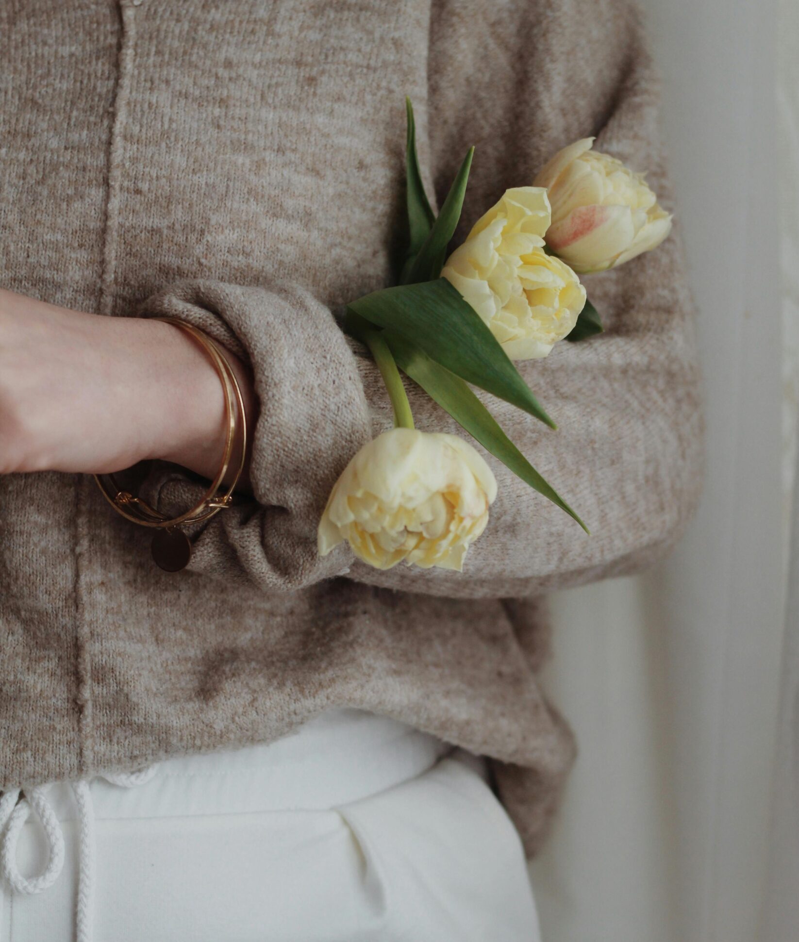 A person holding yellow tulips in soft neutral tones, symbolising eating disorder recovery and the journey towards self-compassion and healing.